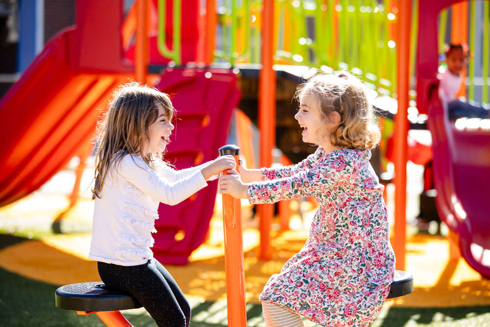 two students smiling on a teeter-totter