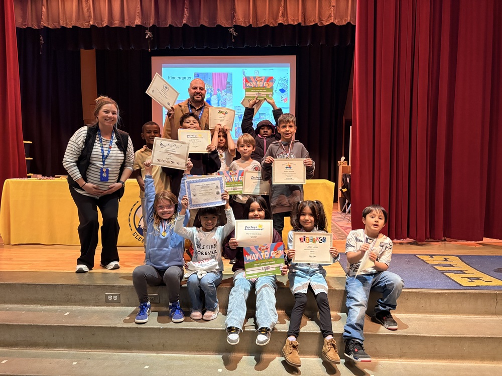 Students holding paper awards and certificates