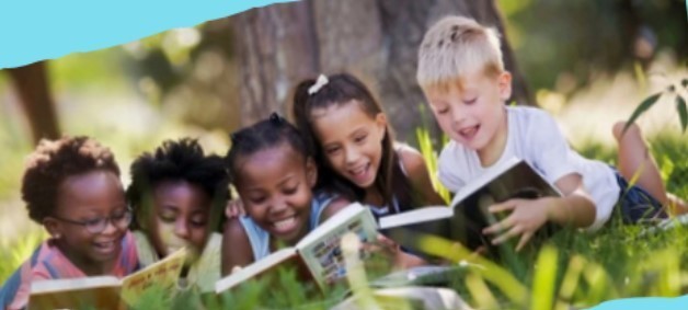 a group of y 5oung children reading books on their bellies in the grass 