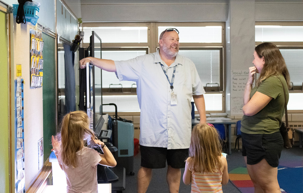 McMeen teacher gestures at the board while a family looks on.