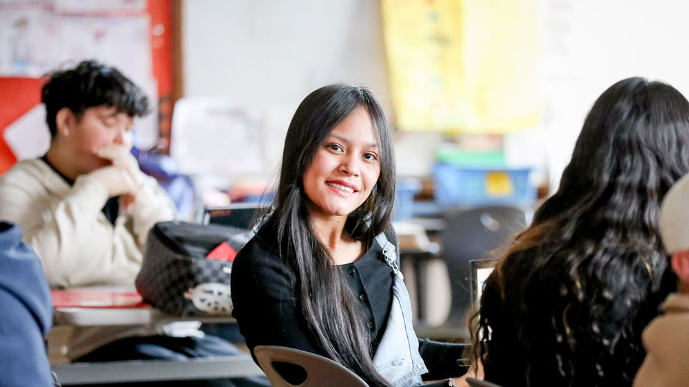 High school student sitting in class facing camera smiling