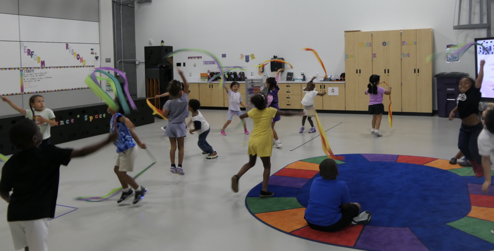 students running around the gym with colorful scarves