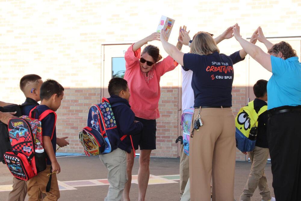 Volunteers making a tunnel for students entering the building on the first day of school 