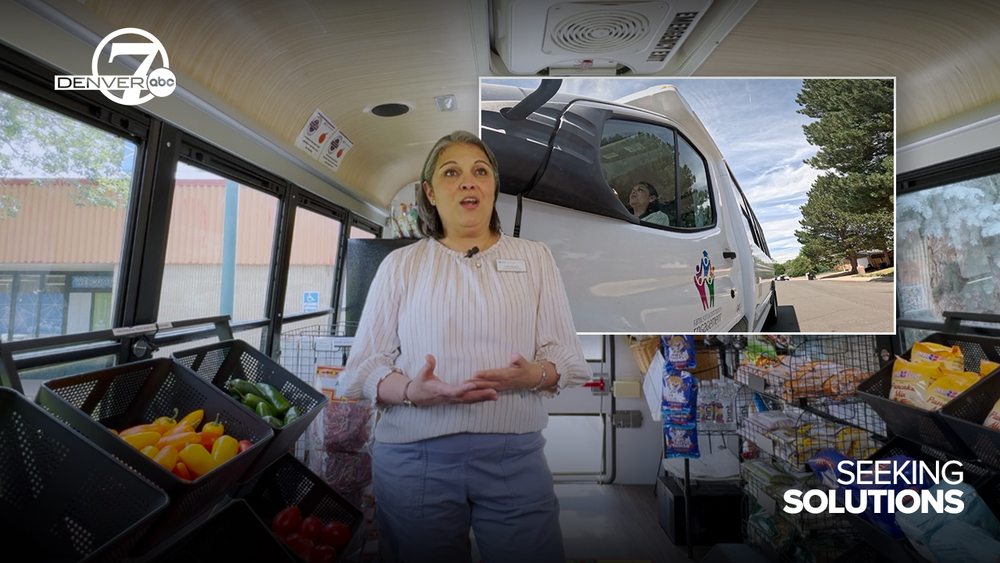 Person speaking in front of food baskets and superimposed picture of van with Denver7 and Seeking Solutions logos