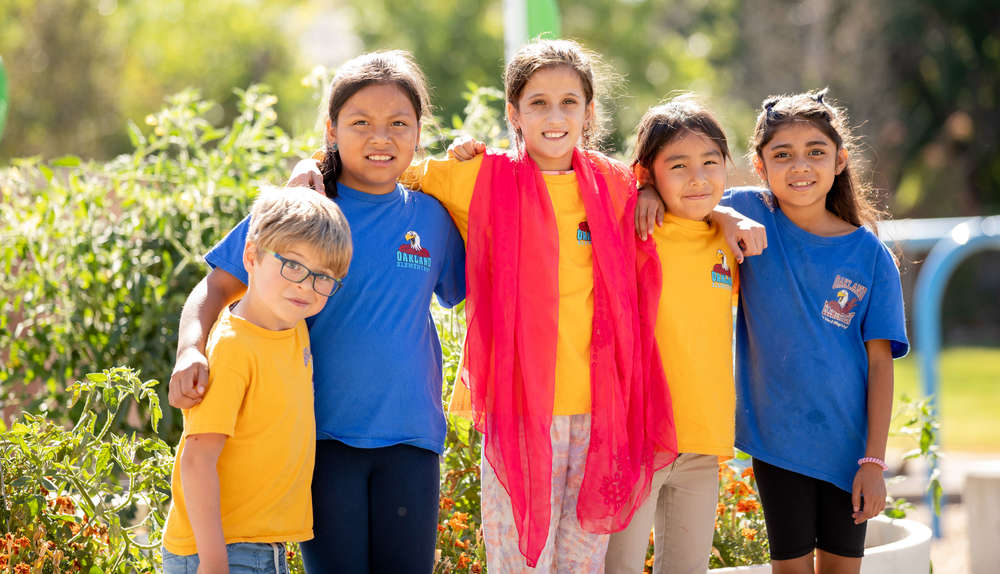 5 elementary students standing together outside