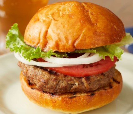 A burger with lettuce, onions, and tomatoes. 