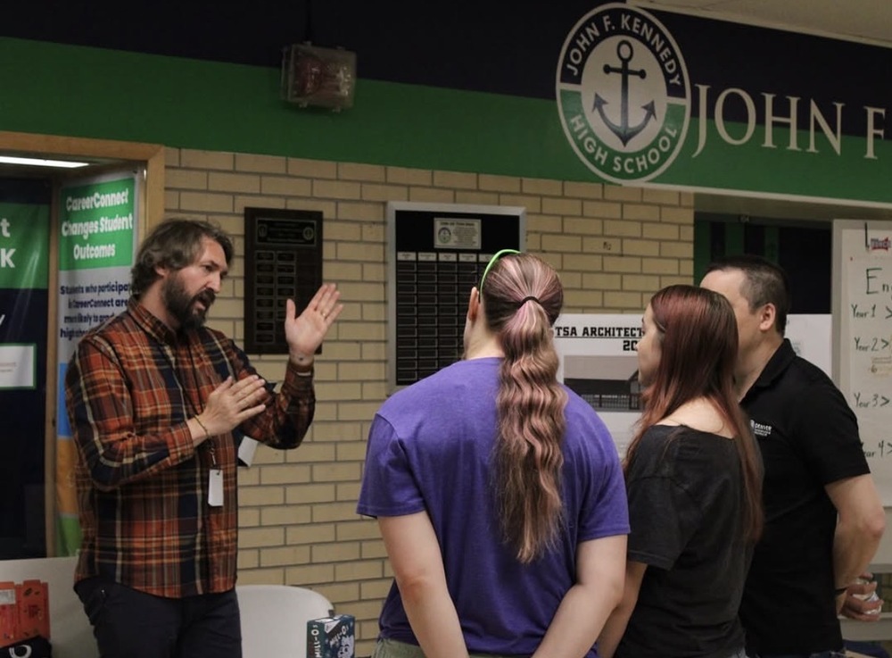 JFK teacher talking to group of adults