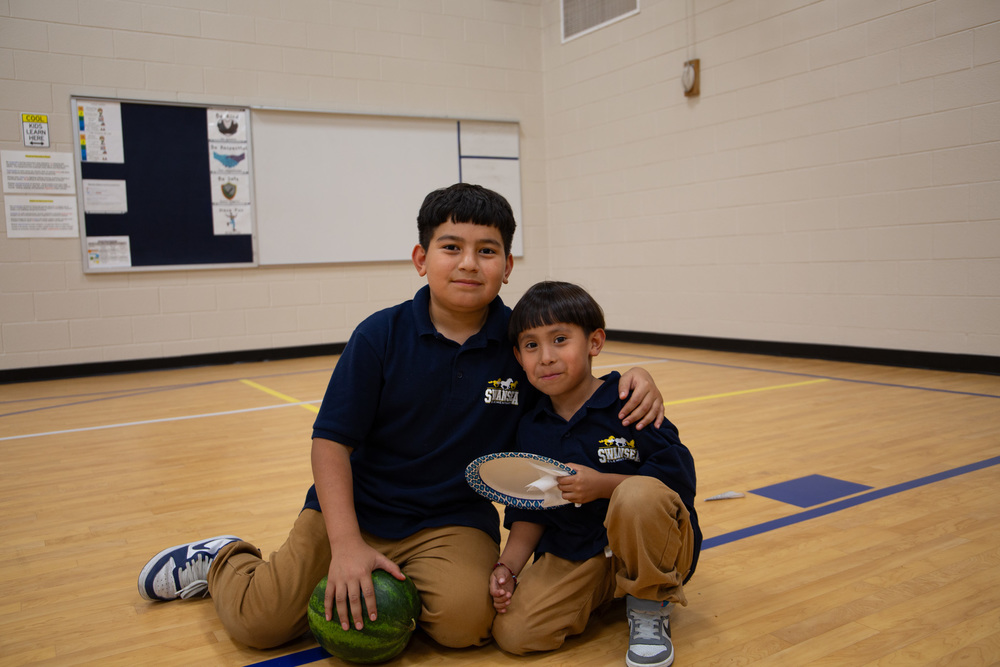 Two Swansea students pose for a photo at K-3 Literacy night after eating pizza.