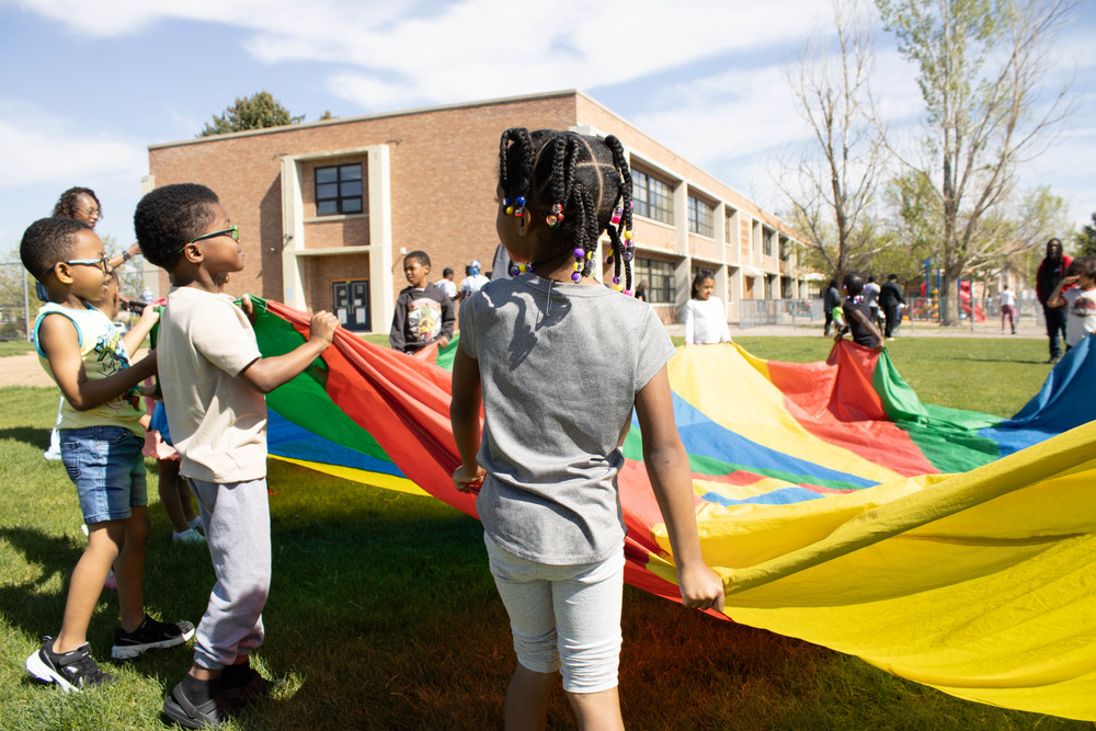 Hallett students playing with a parachute outside the building