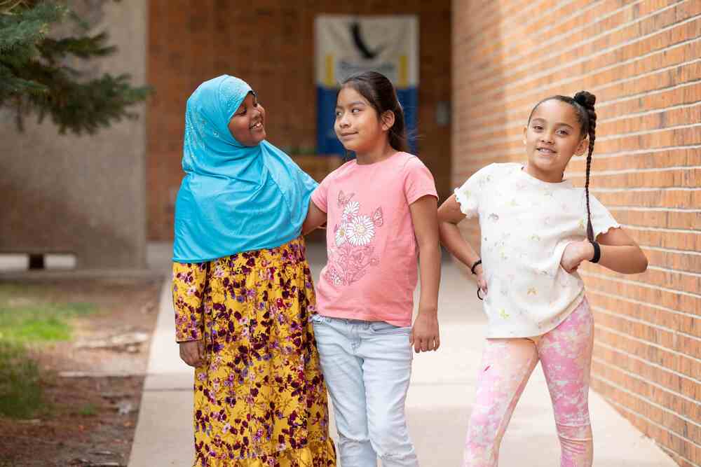 Three students in front of a school