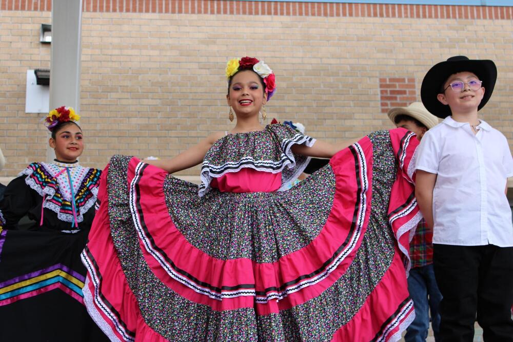 Student in a traditional Mexican dress smiling at the camera