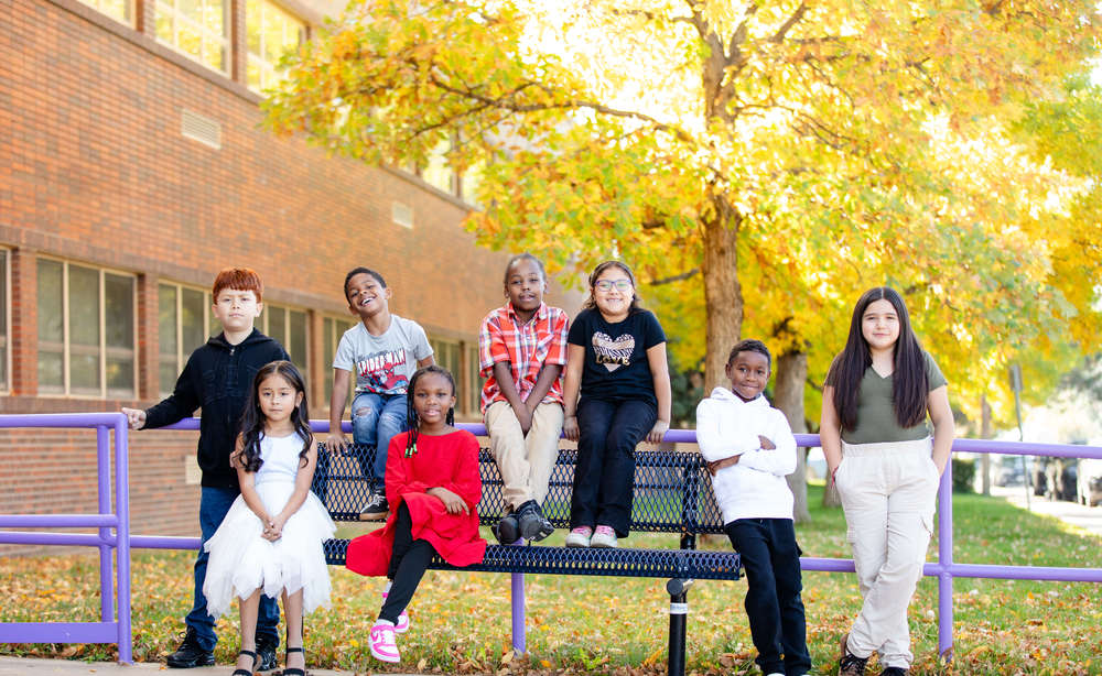 group of students sitting outside of school on bench