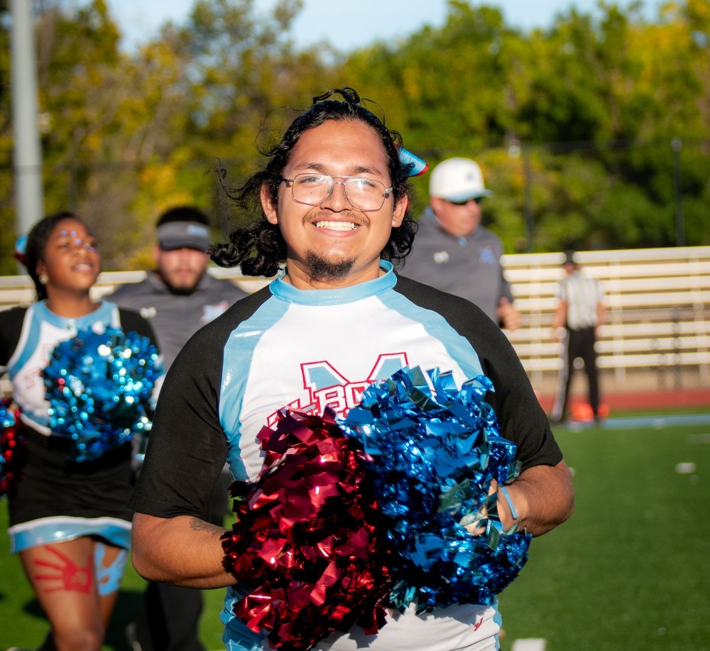 Manual cheerleader smiles holding pompoms