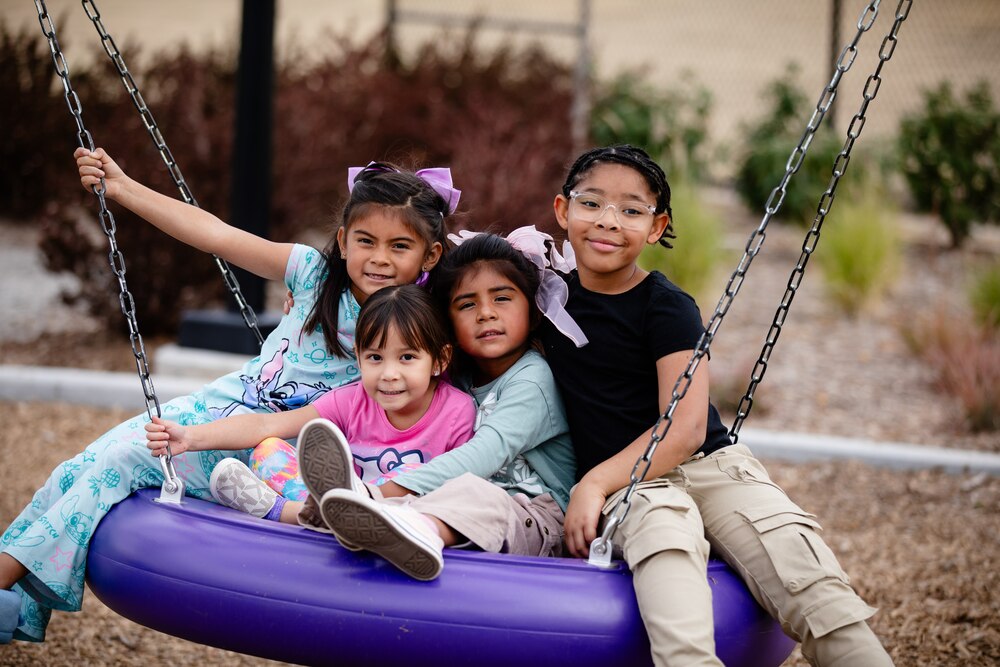Four kids play on a tire swing and pose for a photo