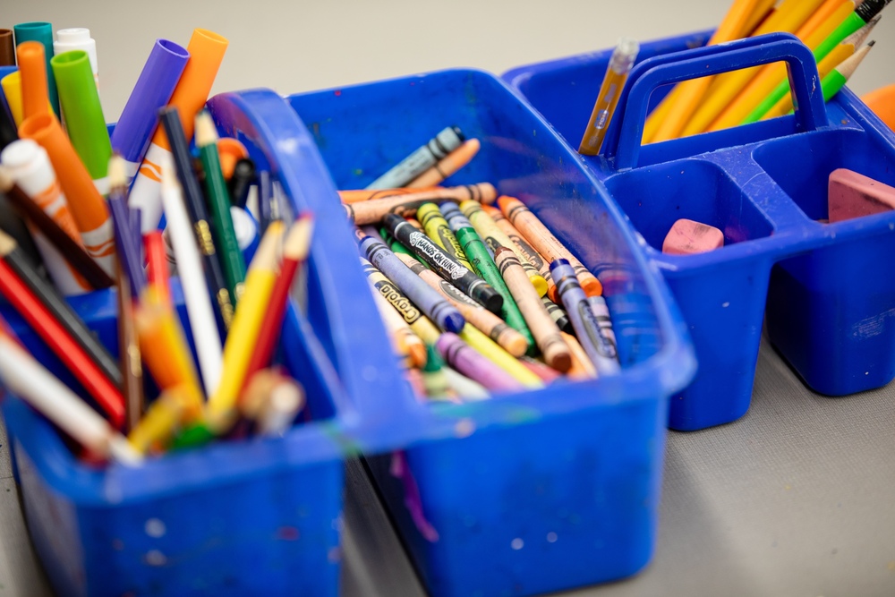 markers, crayons and colored pencils in a bin