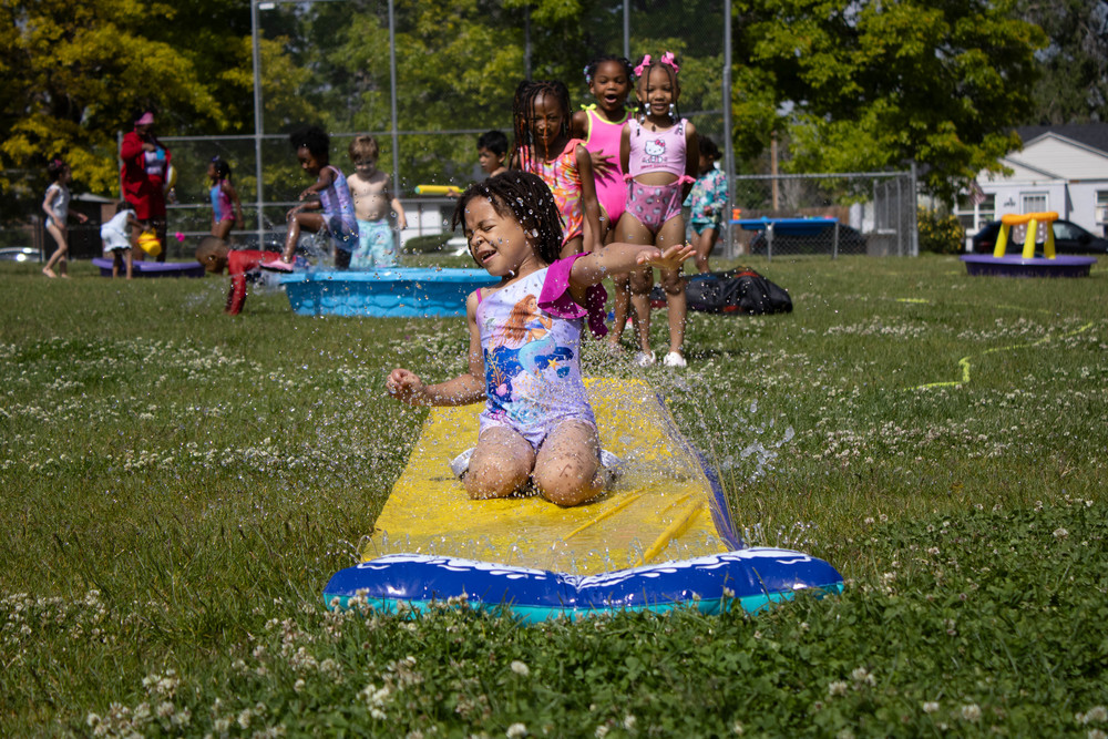 Hallett student sliding on the slip n slide with a line of students behind her