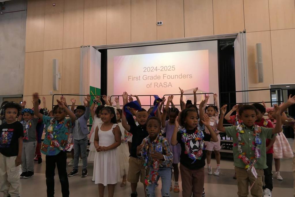 students at the 2024-25 First Grade Fundraiser standing in a group with their arms up dancing