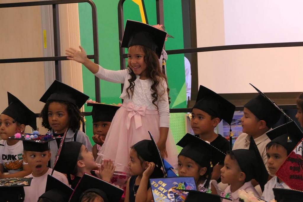 student waving alongside group of other graduating students