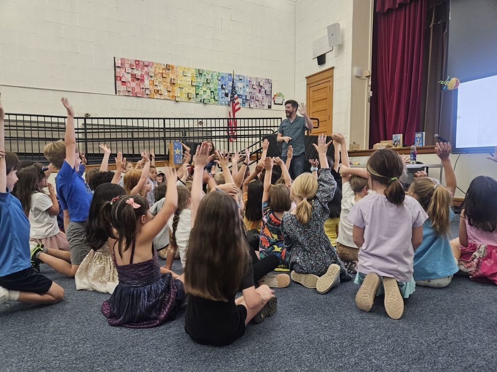 Mat Heagerty  speaking to a group of kids raising their hands