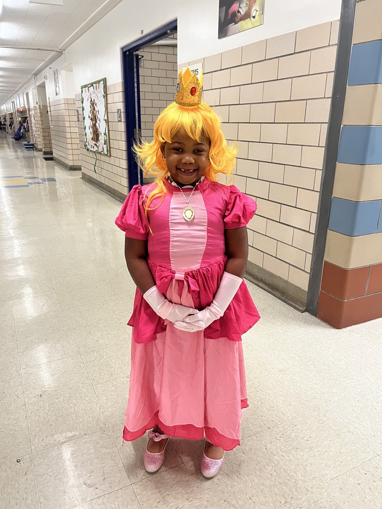 A student poses in a costume in the hallway. 