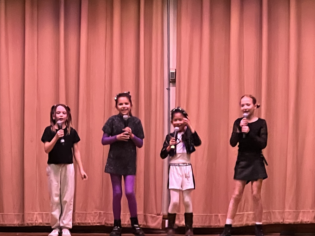 4 fourth graders singing on stage