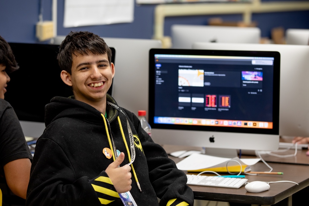 Student in front of computer smiling