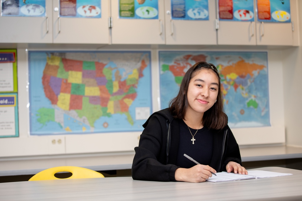 Student writing on paper at desk