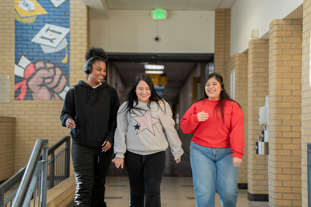3 CEC female students walking in the hallway, smiling and conversing