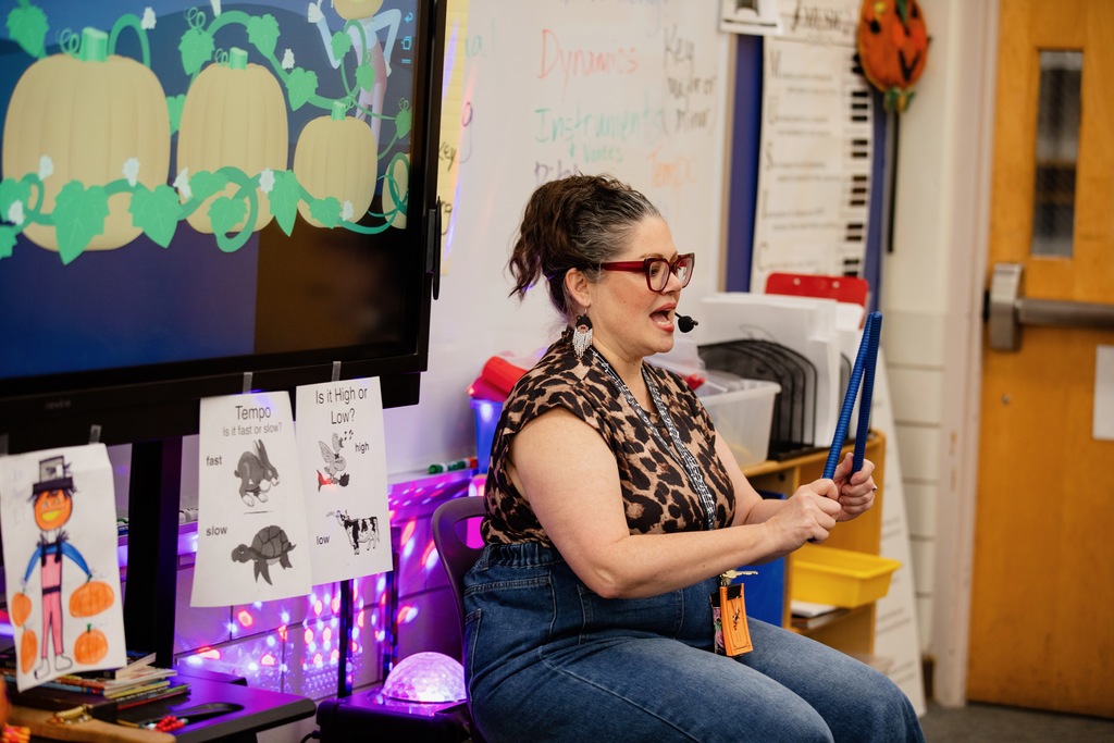 teacher demonstrates drumsticks for a music class