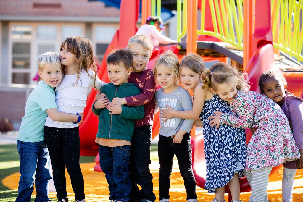 kids gather for a group hug in front of a playground