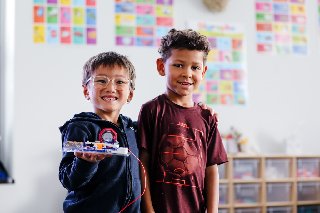 two young boys show off a circuit board