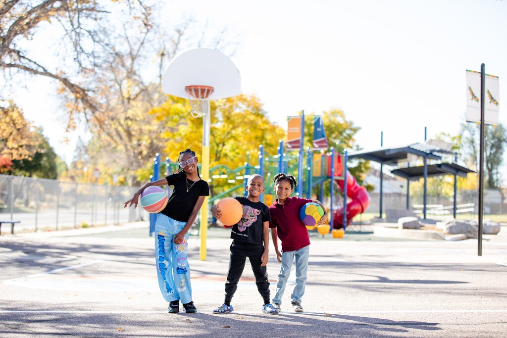 kids pose in front of a basketball hoop on an autumn day