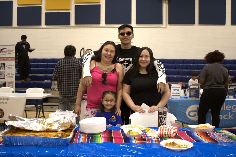 family poses with their potluck food