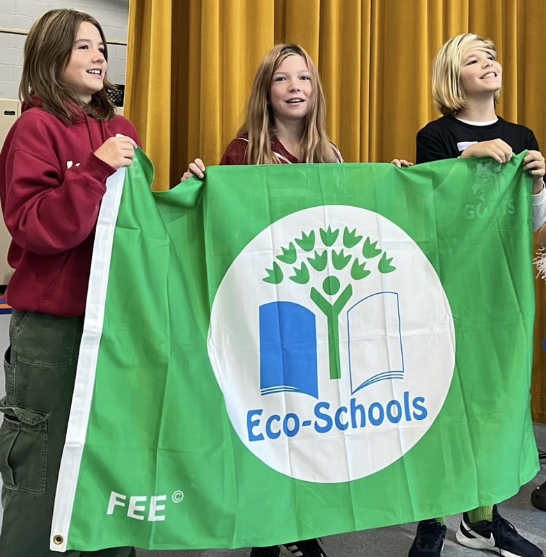 Three people holding an Eco-Schools flag