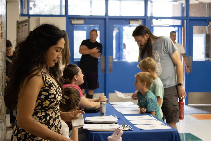 McMeen teacher smiles down at her table while families gather in the background.
