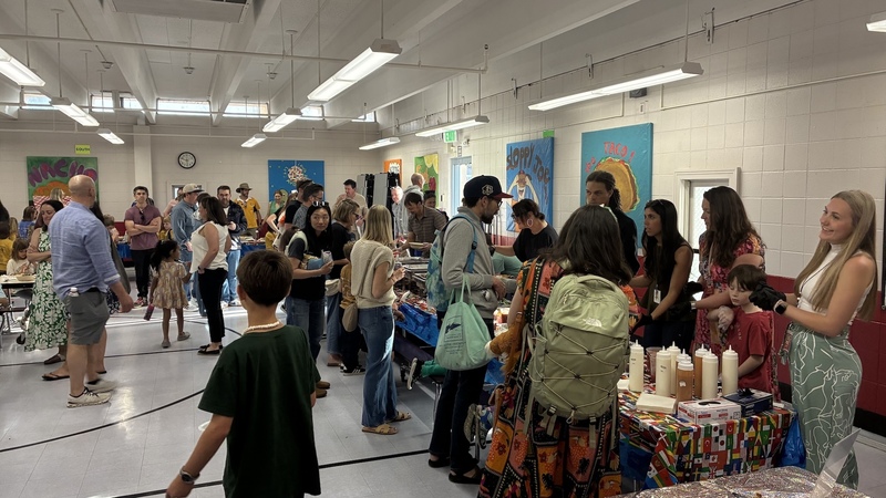 Large group of people standing around a set of tables