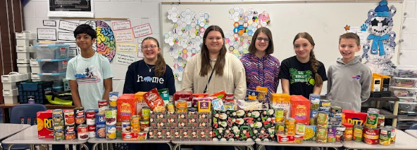 DMS students pose for a photo in front of non-perishable food items