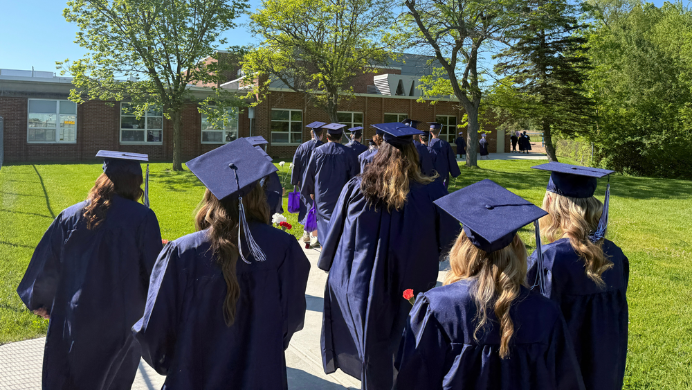 Seniors walk in their graduation gowns.