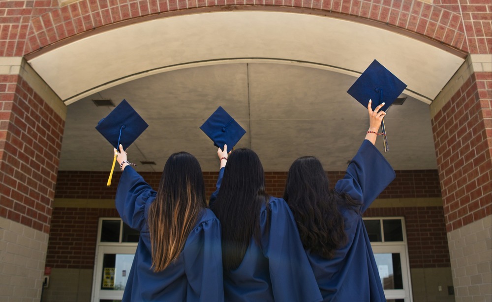 students holding up caps, with picture from behind