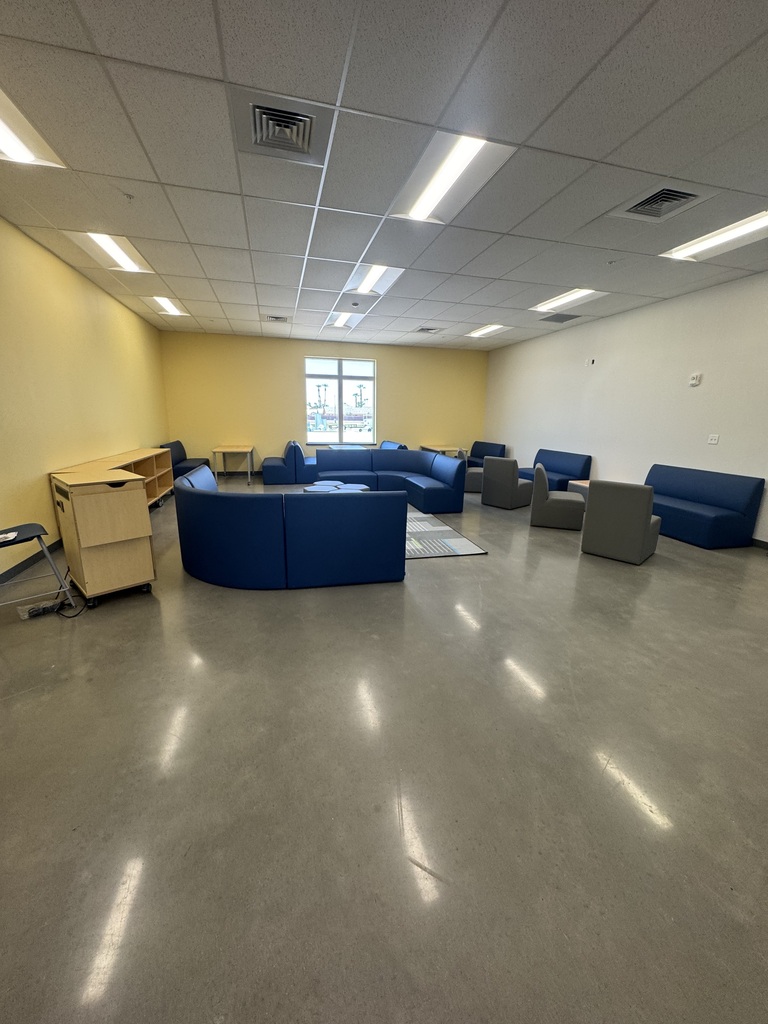 Common area in the school with yellow walls, desk and seating. 