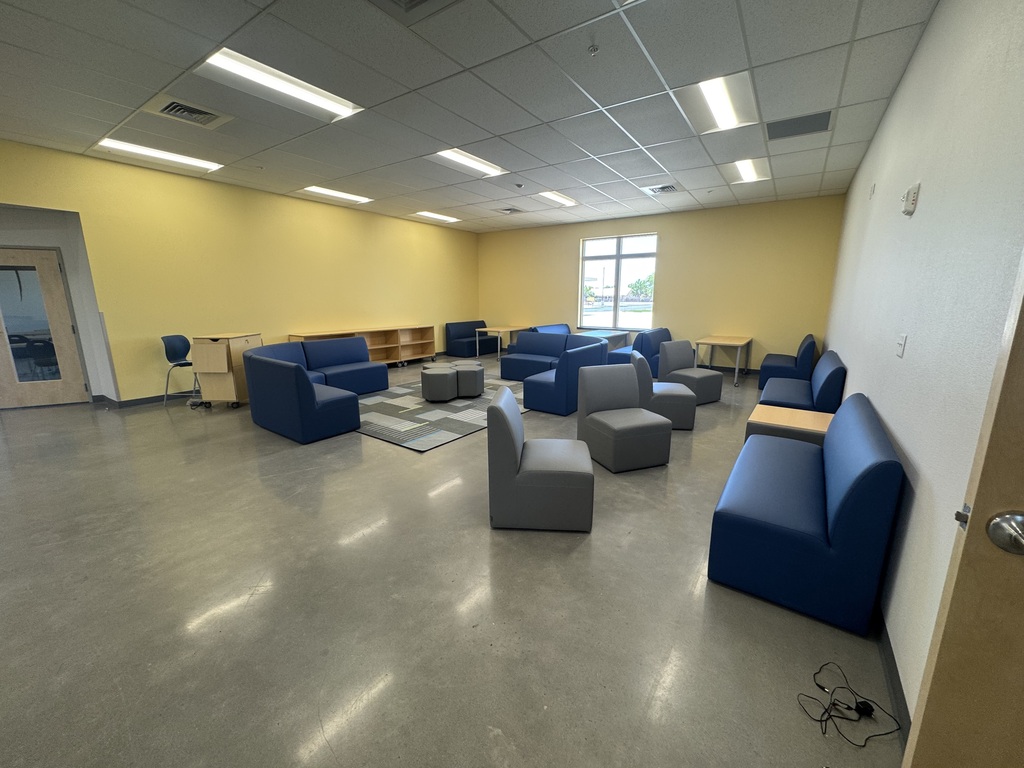 Common area in the school with yellow walls, desk and seating. 