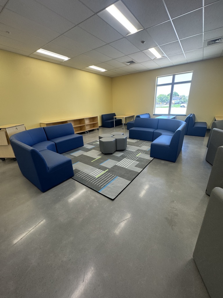 Common area in the school with yellow walls, desk and seating. 