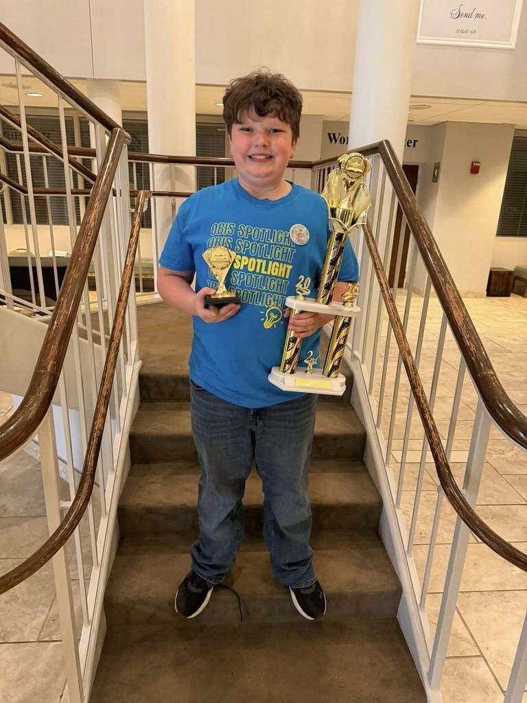Knowledge Bowl student with trophies