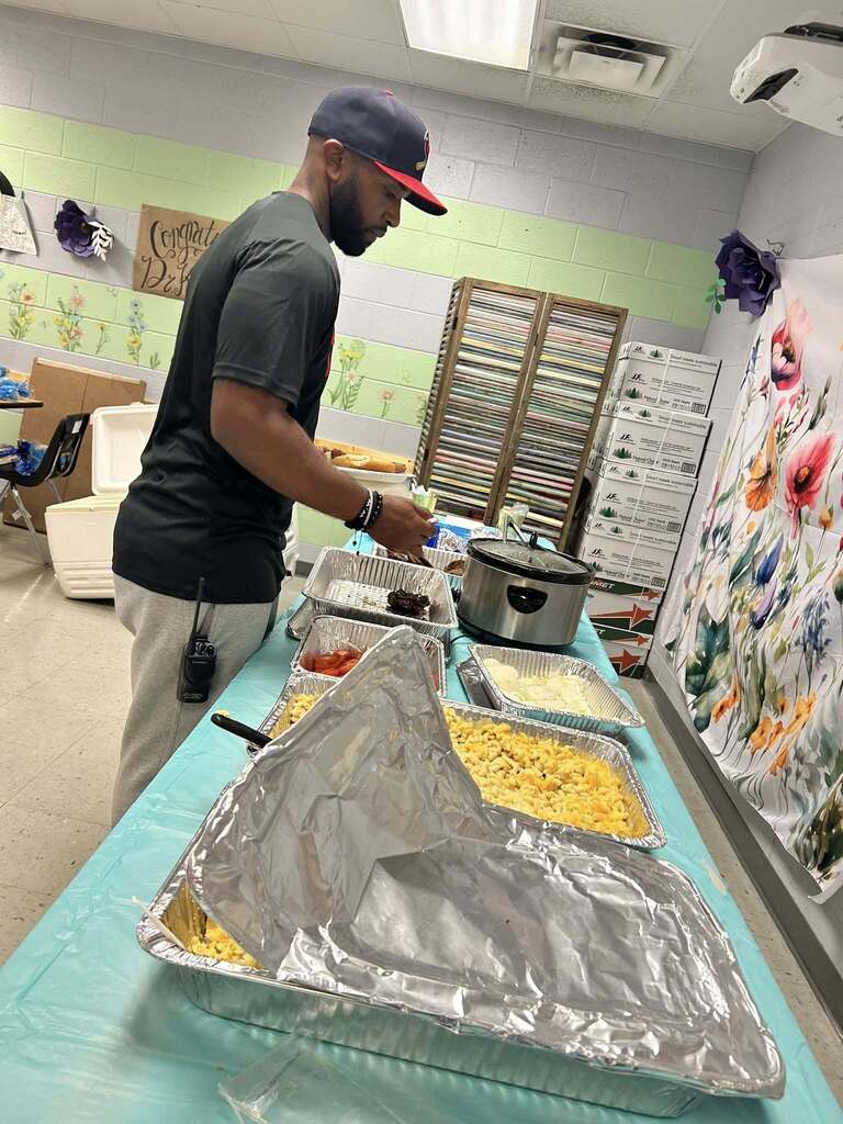 Assistant Principal Mr. Patton standing at a table with various trays of food