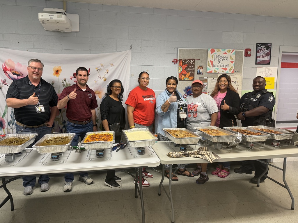 Center Hill Middle School teachers and staff standing behind a table with trays of food 