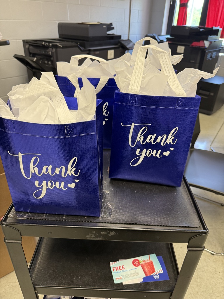 Two blue gift bags with the text "Thank You" in a white script font on a cart.