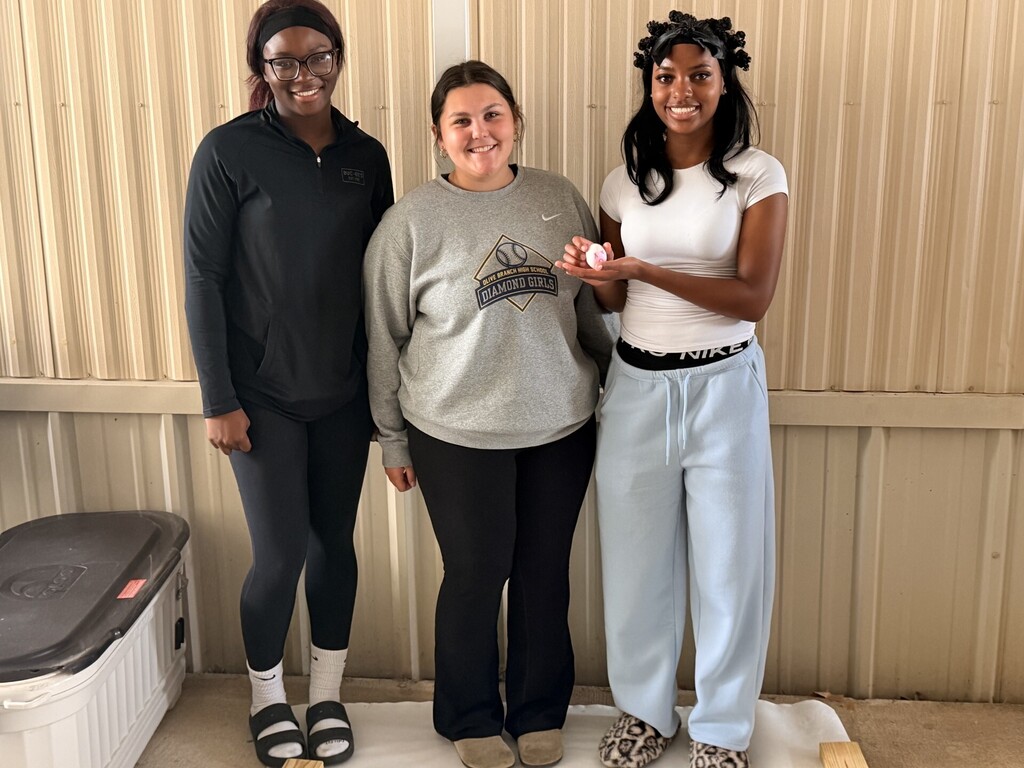 three students posing showing their egg