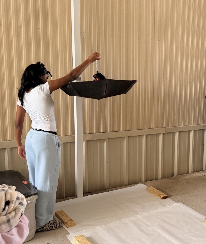student about to drop umbrella with egg inside
