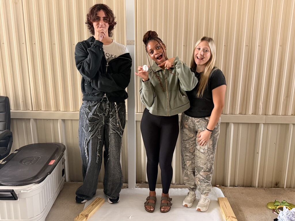 three students posing showing their egg