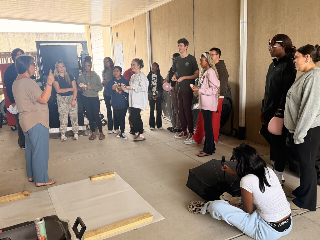 students gathered listening to teacher instructions for "humpty dumpty" teamwork exercise